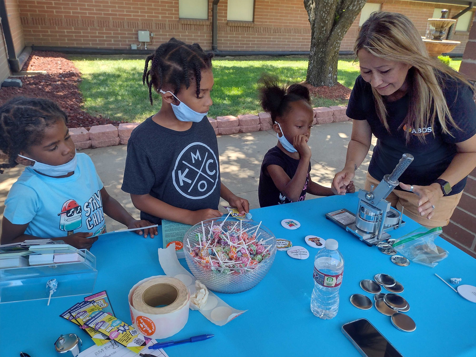 three children making a button with an adult
