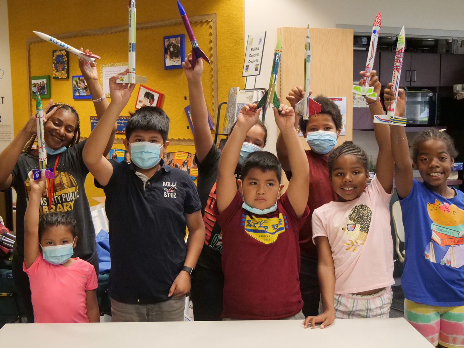 group of children stand holding rockets