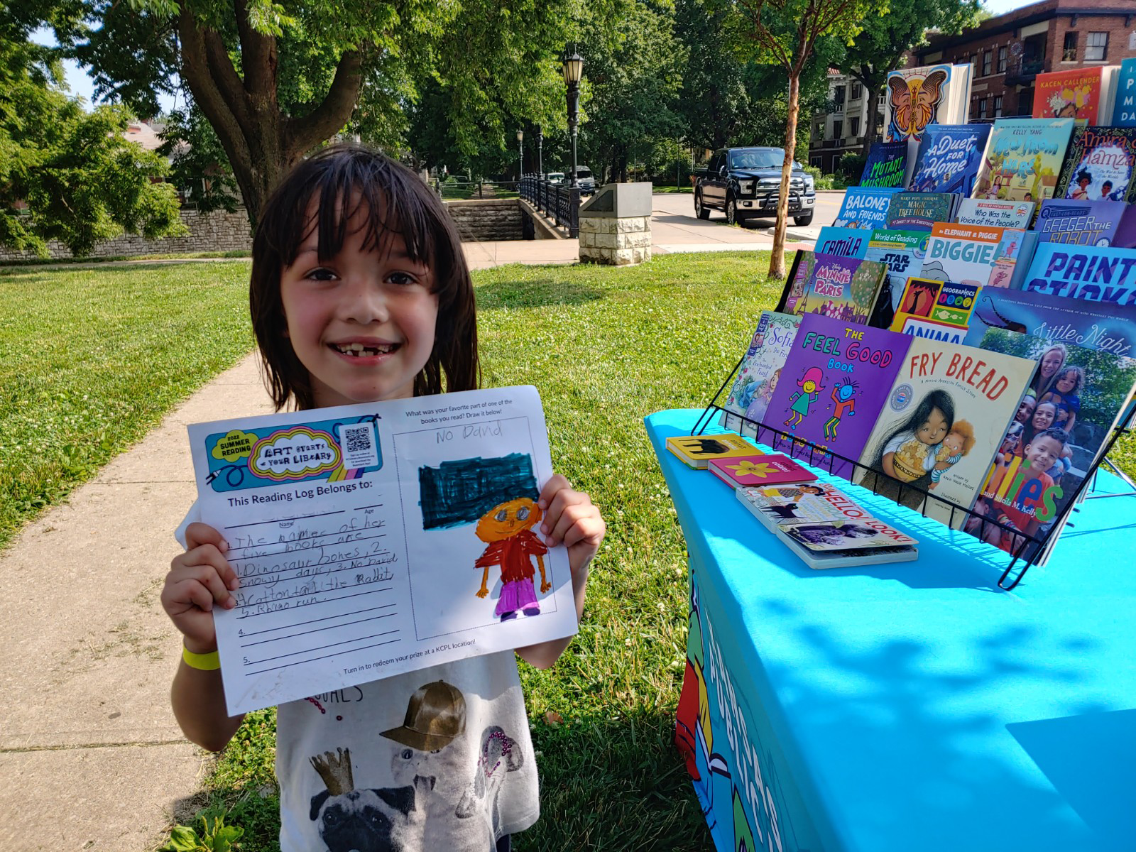 smiling child stands by table with books on display