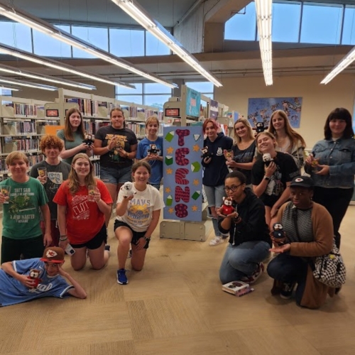 KC Library teens hold Summer Reading prizes ranging from stuffed owls to pint glasses.