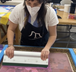 Artist in a mask using a screen printer