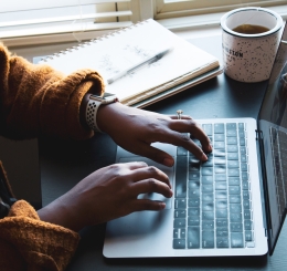 person using laptop with coffee nearby