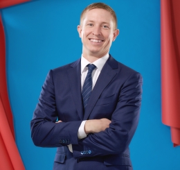man smiles in front of coiled red paper