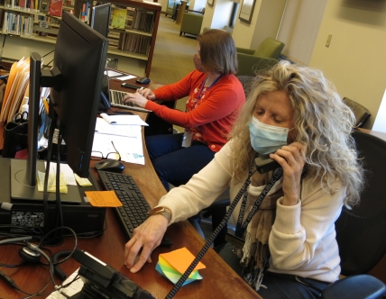 People at a desk behind computers and on the phone