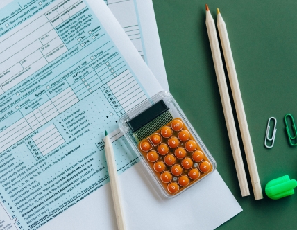 calculator and pencils on green desk with papers