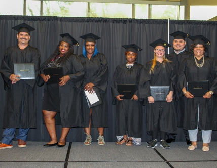 Seven graduates in caps and gowns