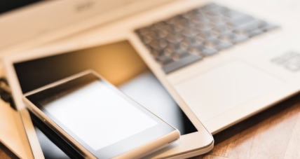 laptop, tablet, and phone stacked on table