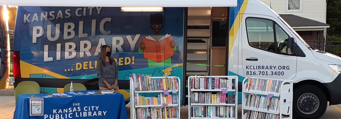 bookmobile with books on carts and staffer behind table