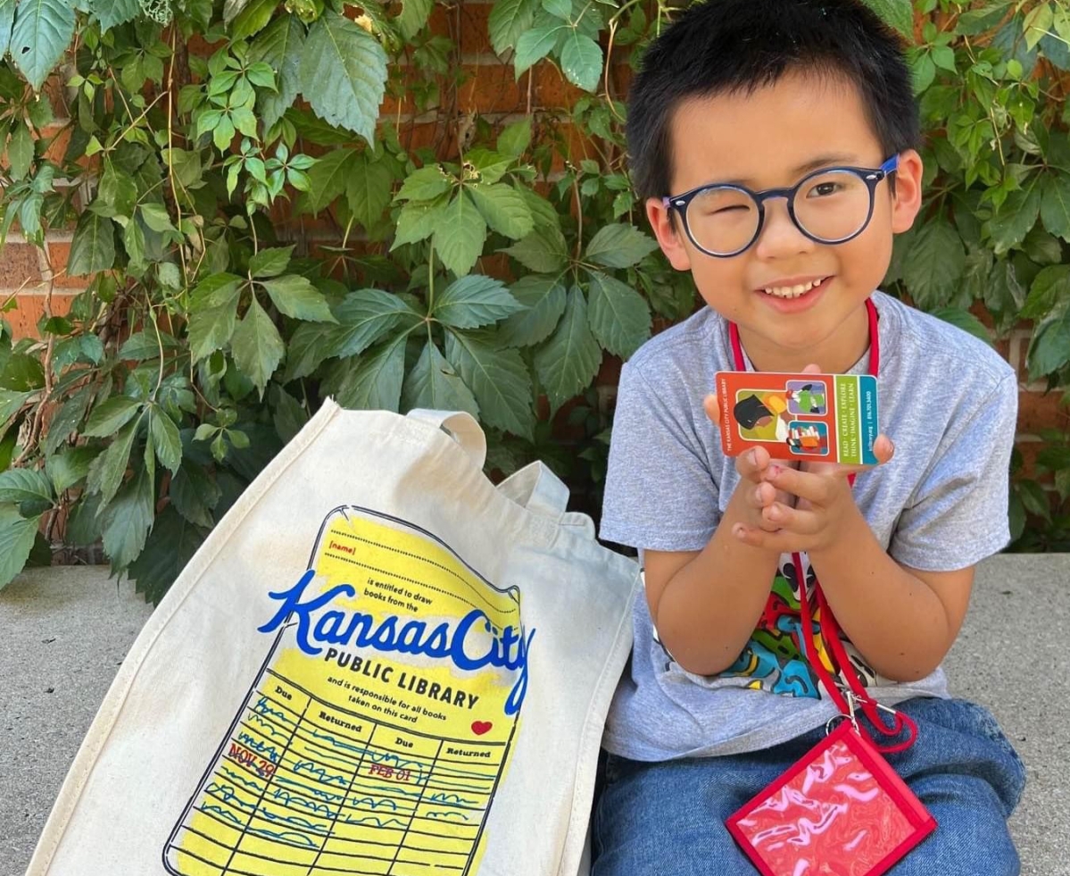 child with library card and bag