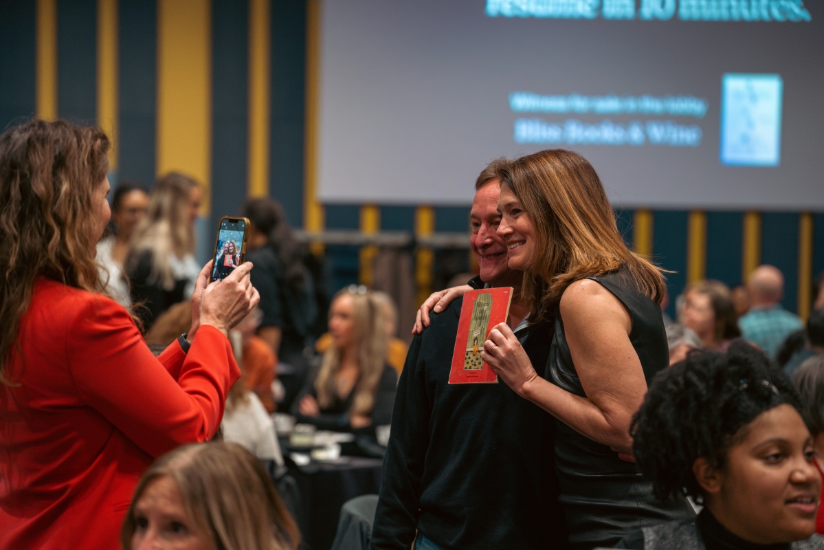 woman and man pose for photo with book