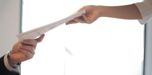 person handing paper to another